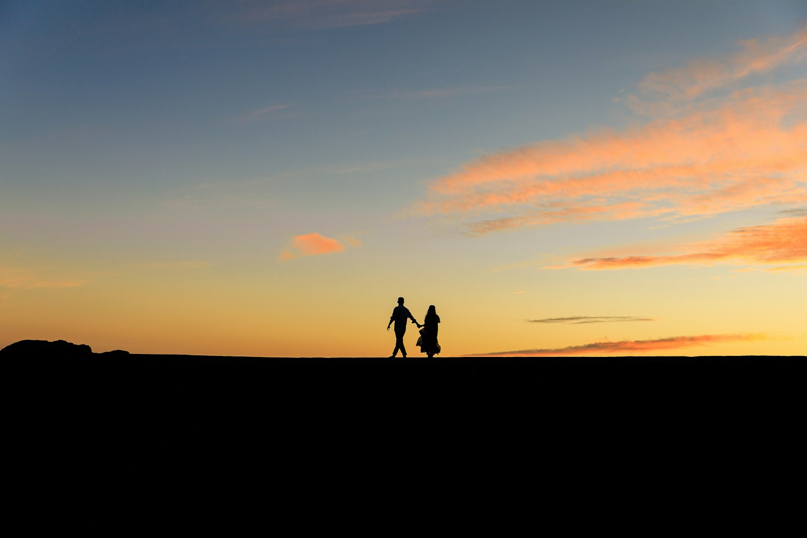 Zwei Menschen halten sich bei Sonnenuntergang an den Händen